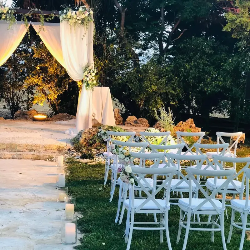 חופה רומנטית בחוץ עם כיסאות לבנים ונרות